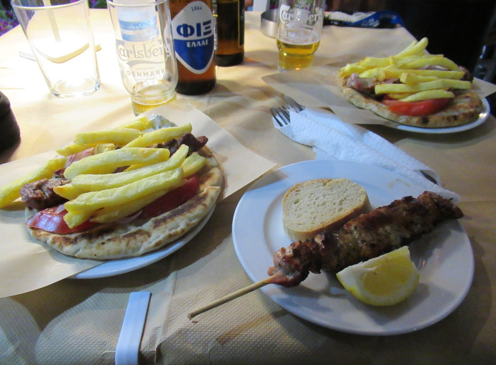 Teller mit Souvlaki-Spießen und ein Glas griechisches Bier in einer kretischen Taverne